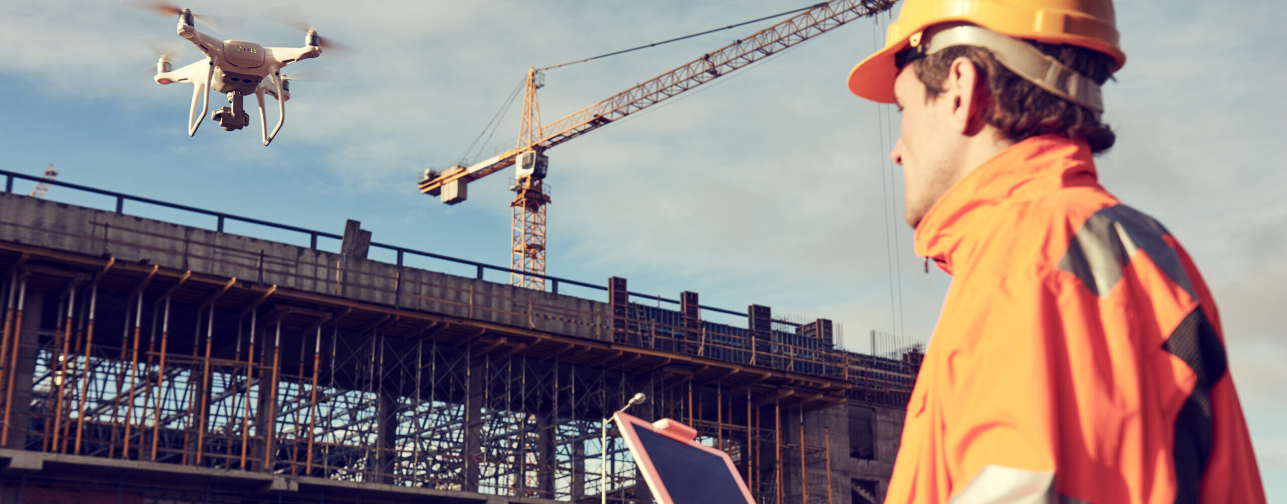 A man working in construction using a drone to survey a building site